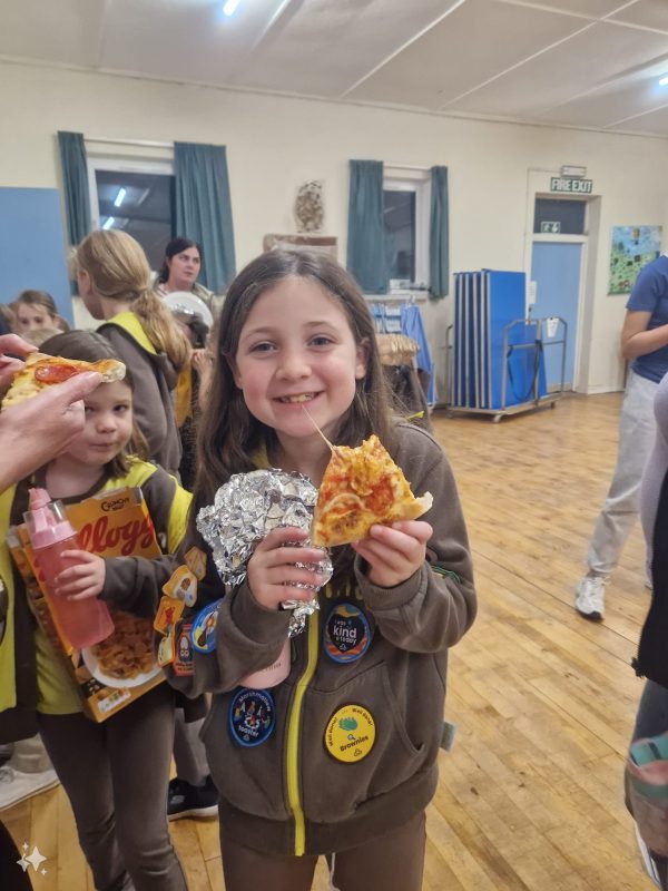 A Brownie smiles while eating her pizza