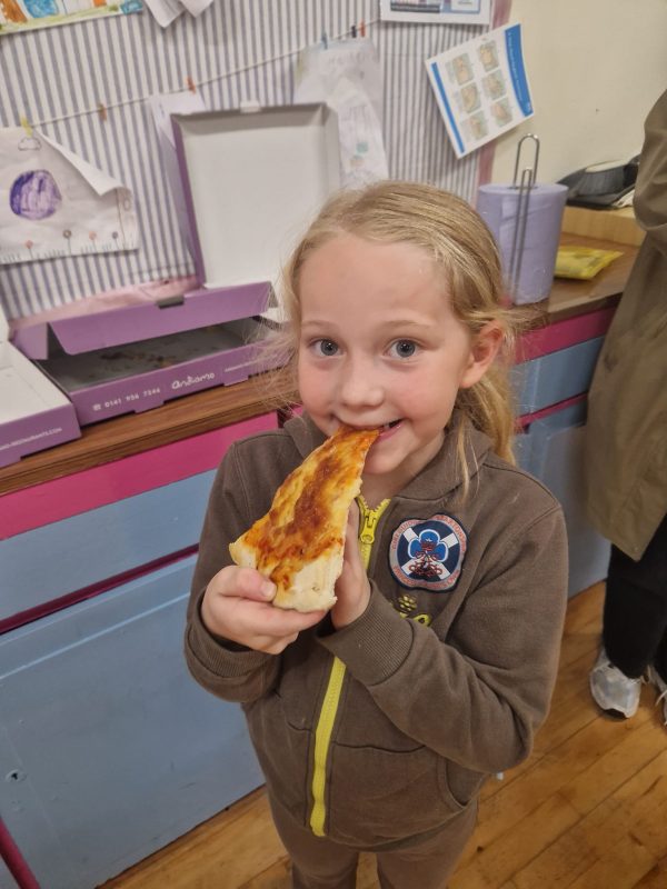 A Brownie smiles while eating her pizza