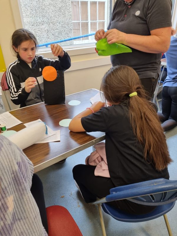 A group of girls stand around a table doing a craft